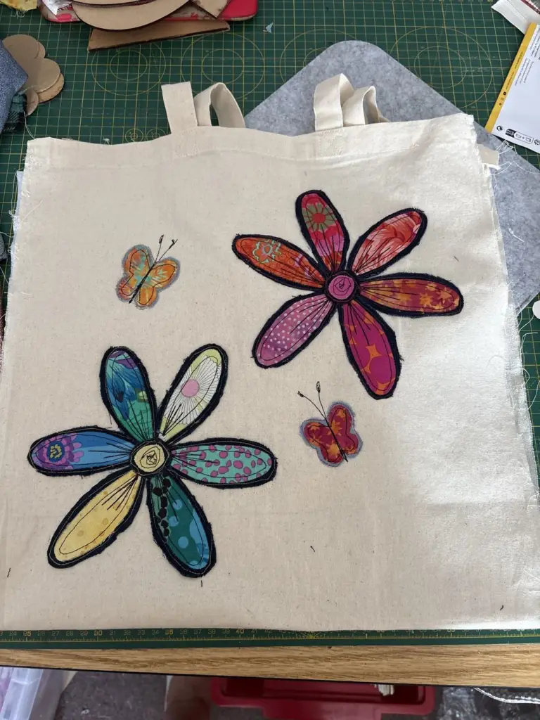 A canvas tote bag with appliqué flowers and butterflies