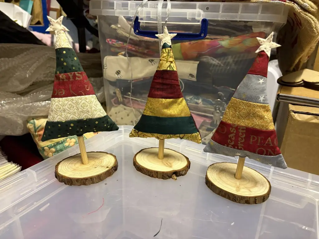 Three patchwork fabric Christmas trees on wooden log bases