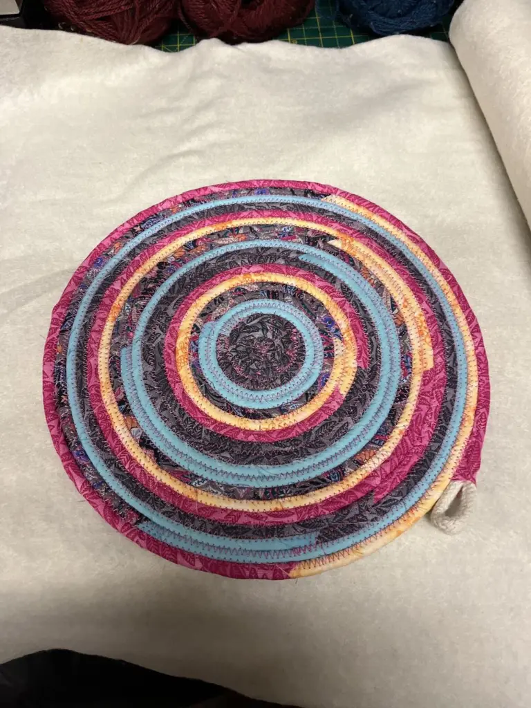 A round fabric rope placemat with pink, purple and blue rings
