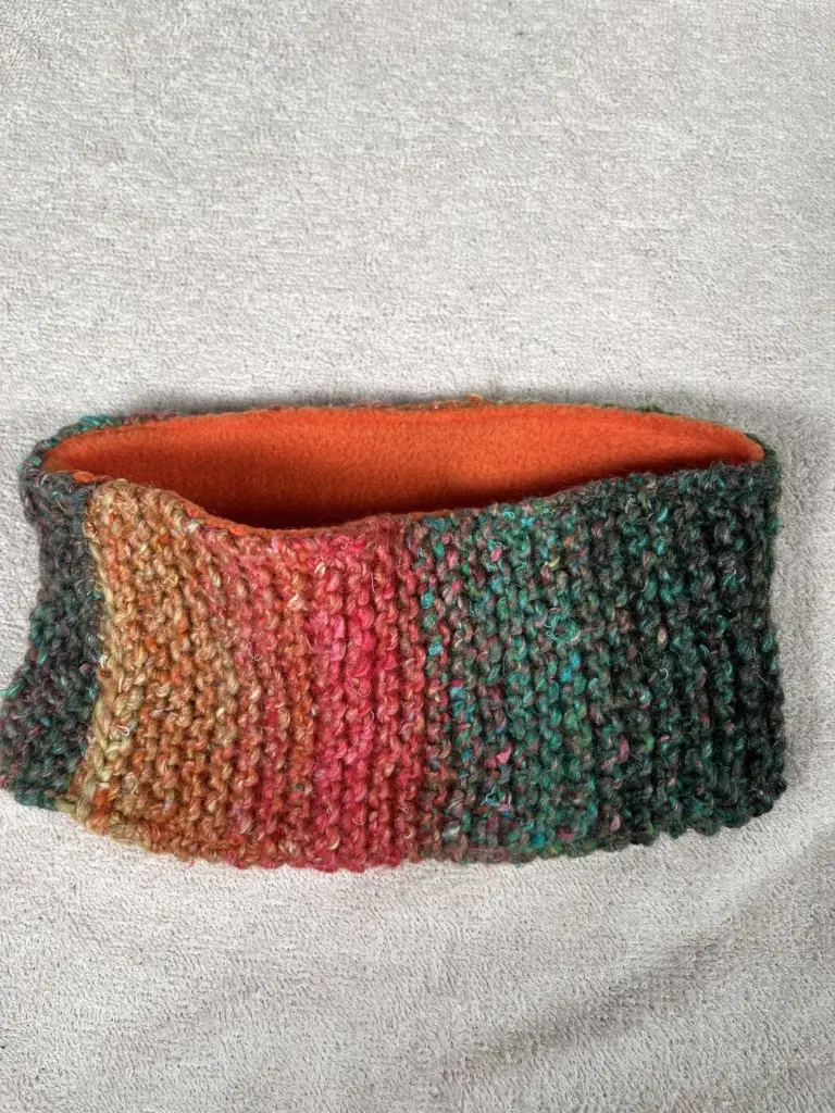 Hand knitted headband in red and green with a bright orange lining