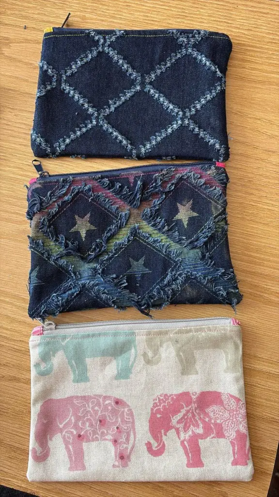 Three sewn zip pouches: two in fringed denim and one with pink elephants